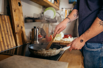 close up of man frying onion in pan