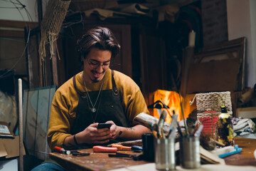 man using smartphone in his workshop