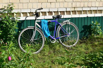 The bike stands near the wall of the house.