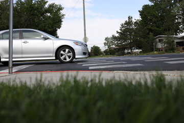 Side view of a silver car driving in the neighborhood