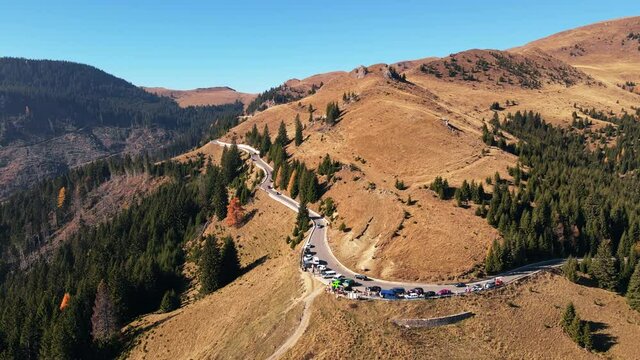 Aerial drone view of a road in Bucegi Mountains in Romania. Parked and moving cars, green firs