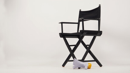 Black director chair and yellow megaphone on white background.