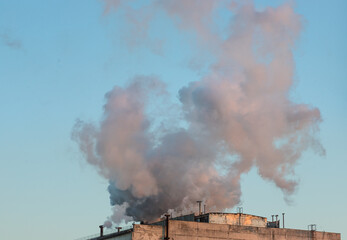 Fototapeta premium Brick chimney with white smoke over an industrial building