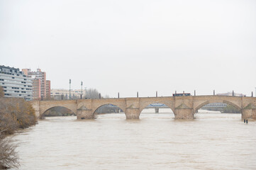 Fototapeta premium Basilica del Pilar in Zaragoza, and the stone bridge in northern Spain, on a cloudy day.