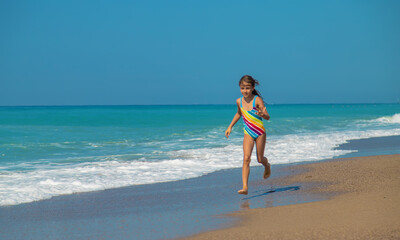 Fototapeta na wymiar The child runs along the beach near the sea. Selective focus.