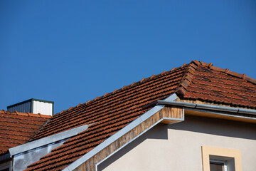 Obraz premium Ceramic tile roof with chimney and white wall, blue sky as background