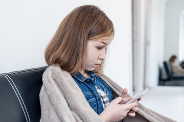 A teenage girl looks at the smartphone screen in surprise.