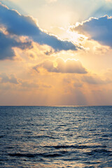 Beautiful fluffy clouds and blue sea on sunny day at golden hour painted with sun in deep and bright colors