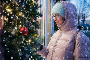 Pretty Woman near illuminated new year decorated window. Xmas holidays, or shopping on New Year or Christmas concept