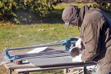 A man saws a ceramic tile with a circular saw