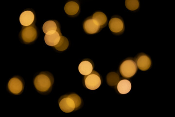 Bokeh golden lights background. Blurred lights Christmas garland on a black background.