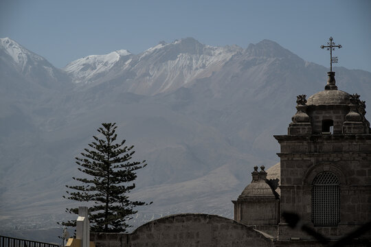 Spanish colonial church tower with snow capped andes mountains in background in cusco peru traditional religion converted to Christianity by conquistadors.