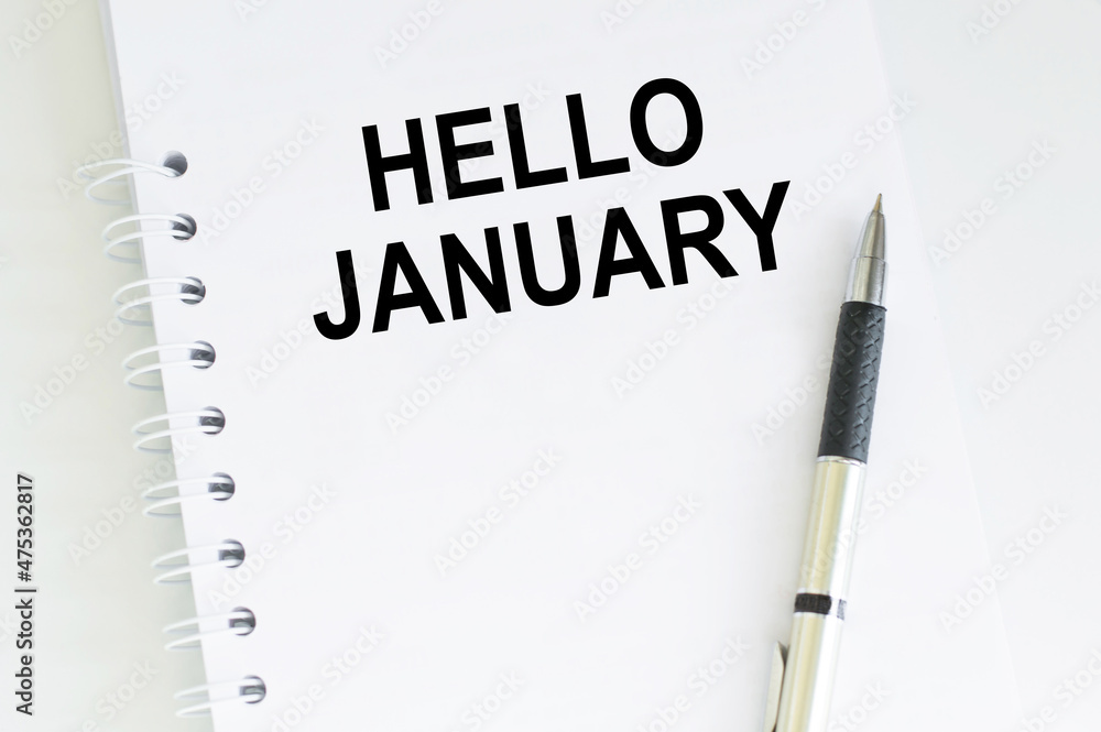 Poster hello january text on notepad next to pen on desk