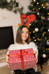 The young girl gives a red Christmas gift on a camera