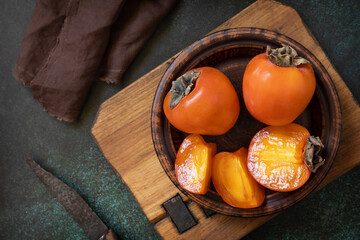 Fresh organic ripe Persimmons fruits in wooden bowl.