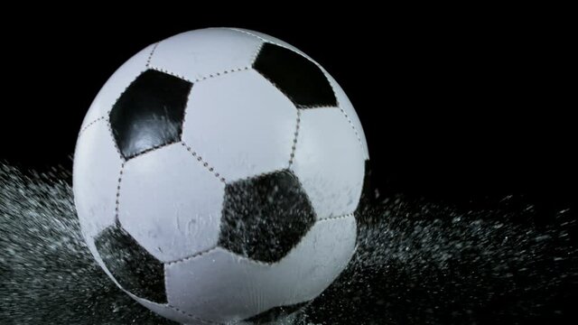 Super slow motion of falling soccer ball on water surface, black background. Filmed on high speed cinema camera, 1000fps.