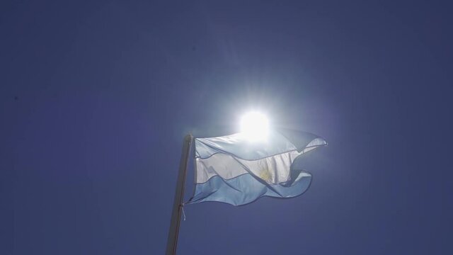 bandera argentina flameando sobre sol, cielo azul