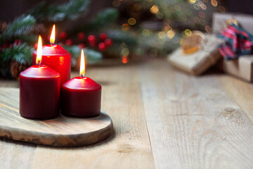 Magic Christmas. three red burning candles, christmas tree and gifts.