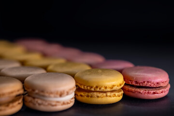 chocolate, coffee, vanilla, lemon and strawberry macaroons on black background