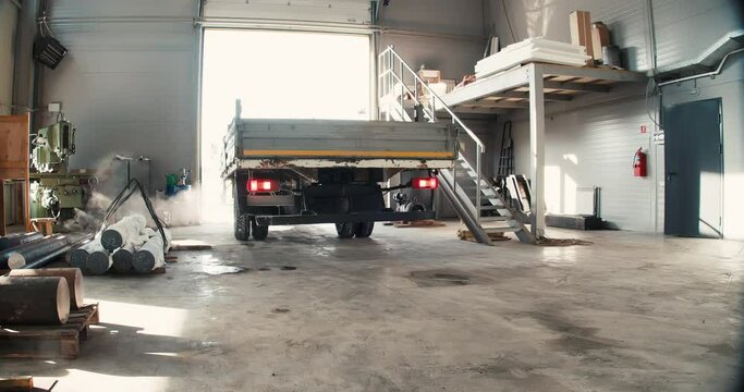 A truck pulls up to unload metal pipes at a sheet metal factory.