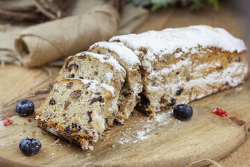 Christmas stollen with a mixture of dried fruits, nuts and powdered sugar on a board.