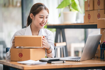 Small start-up business owners using computers at work, freelancers, saleswoman, checking production orders. Pack products for delivery to customers