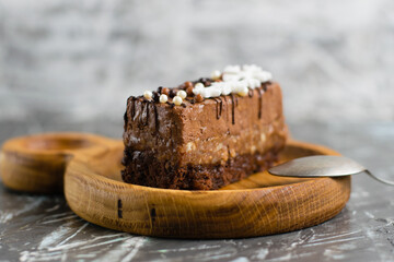 Delicious chocolate cake with winter decor snowflakes on wooden plate with spoon on gray background with copy space, side view close-up
