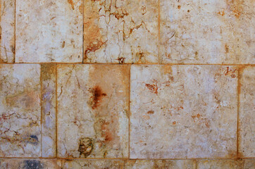 Detailed view of yellow ancient wall. Old wall of large light blocks of marble tiles. Wall with interesting structure. Outdoor and indoor interiors. Grunge texture background