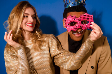 Girl holding mask near face of guy in crown
