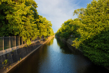 Summer evening landscape with Obvodny canal among green foliage in Kronstadt, Russia