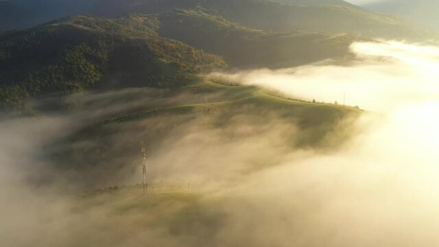 Aerial view on amazing flowing morning fog spreads over green meadows in autumn mountains. Ukrainian Carpathian mountains. UHD 4k video
