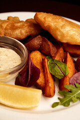 battered fish on a plate with chips on a wooden table in pub. unhealthy food