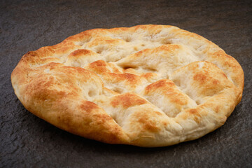 Turkish traditional pita bread on stone surface. Round flat bread on dark textured table surface