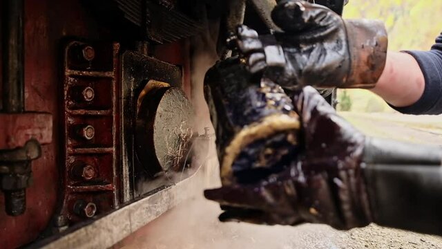 Mechanic adding oil in mechanisms of stopped steam train Mocanita at a railway station, Romania. Slow motion
