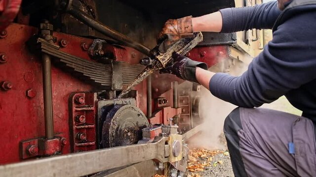 Mechanic adding oil in mechanisms of the stopped steam train Mocanita on a railway station in Romania. Slow motion