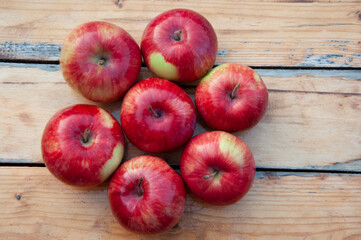 Red apples on a wooden table lie in the shape of a flower. High quality photo