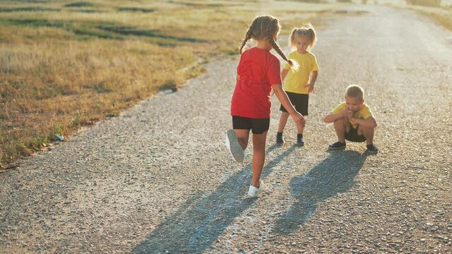 Child on playground play classics. School playground on asphalt. Children draw classics on pavement with chalk. Child is jumping on asphalt.Family of children play classics.School games on playground.