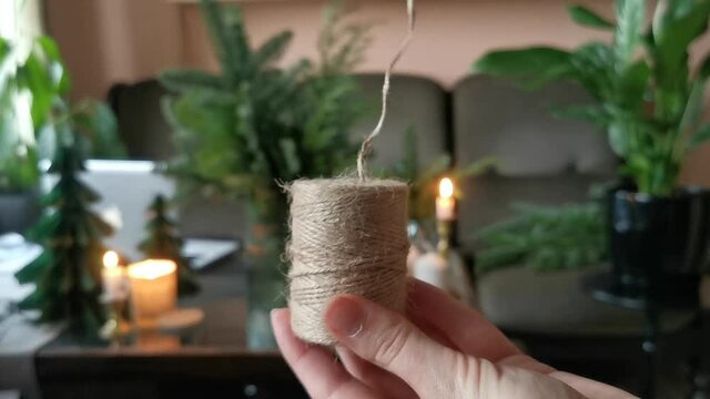 Female hands unwind a skein of twine. Pull the thread. For handmade decoration to the Christmas holidays.