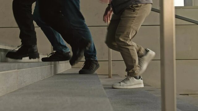 Legs of different people going down the stairs of an underpass or subway.