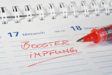 Hamburg, Germany - December 2, 2021: Close-up of a calendar sheet with the german word Booster Impfung