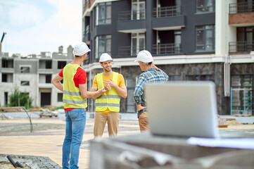 Three men discussing idea at construction site