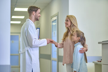 Obraz premium Man shaking hands with woman hugging daughter