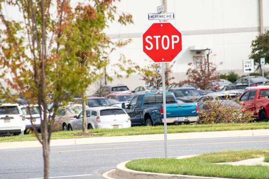Red stop sign on a road near a parking lot