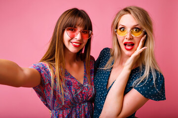 Studio portrait of two positive best friend women having fun at pink background