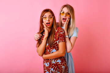 Studio portrait of two positive best friend women having fun at pink background