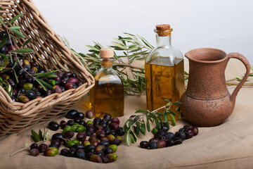 A basket with ripe olives and several old bottles with oil