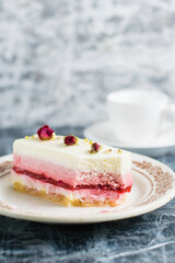 Cutaway sweet mousse cake on vintage plate and cup of coffee on gray background with copy space