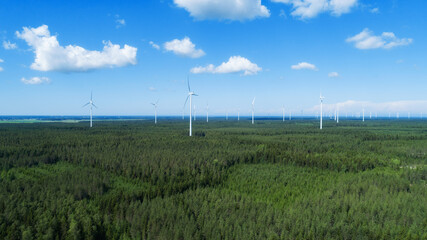 Fototapeta premium Aerial view of windmills in green summer forest in Europe. Wind turbines for electric power with clean and Renewable Energy...