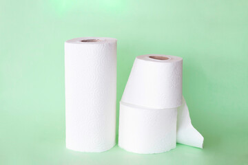 rolls of napkins and toilet paper on green background