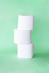 three rolls of toilet paper in a row on green background.